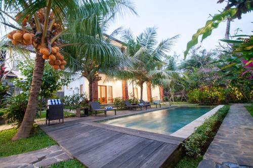 a villa with a swimming pool and a palm tree at Flamboyant Villa Ubud in Ubud