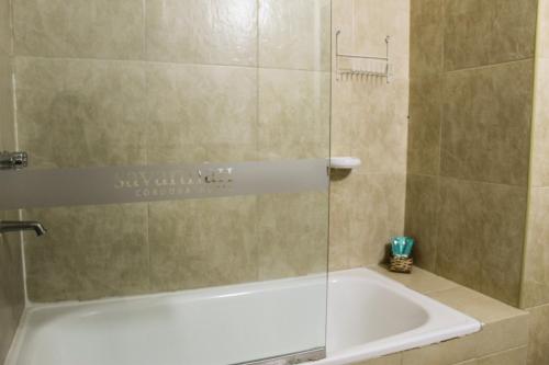 a bathroom with a tub and a glass shower door at Savannah Cordoba Hotel in Córdoba