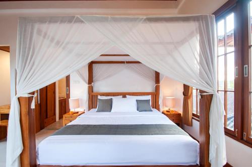 a bedroom with a bed with a canopy at Flamboyant Villa Ubud in Ubud