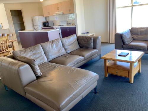 a living room with a leather couch and a coffee table at Bayview Beach House Apartment No 2 in Kingscote