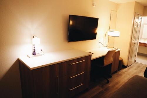 a hotel room with a desk and a television on the wall at All Seasons Inn & Suites in Memphis