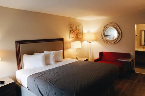 um quarto de hotel com uma cama e uma cadeira vermelha em All Seasons Inn & Suites em Memphis