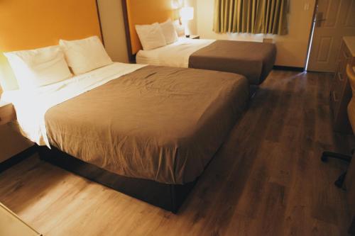 two beds in a hotel room with wood floors at All Seasons Inn & Suites in Memphis