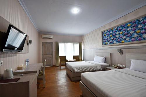 a hotel room with two beds and a flat screen tv at Puri Saron Denpasar Hotel in Denpasar