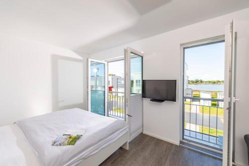 a bedroom with a bed and a flat screen tv at Strandnest in Olpenitz