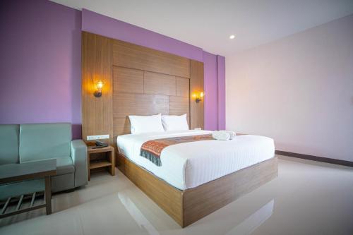a bedroom with a large bed and a chair at Smart Hotel in Lam Luk Ka