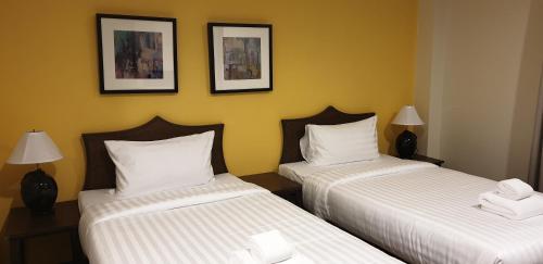 a hotel room with two beds and two pictures on the wall at Vinary Hotel Sukhumvit in Bangkok