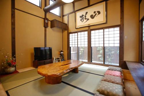 a living room with a wooden table and a tv at Yamagata Kyomachi Hatago Nishijin in Kyoto