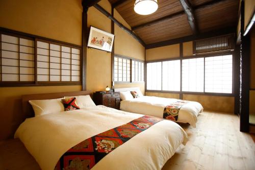 two beds in a room with windows at Yamagata Kyomachi Hatago Nishijin in Kyoto