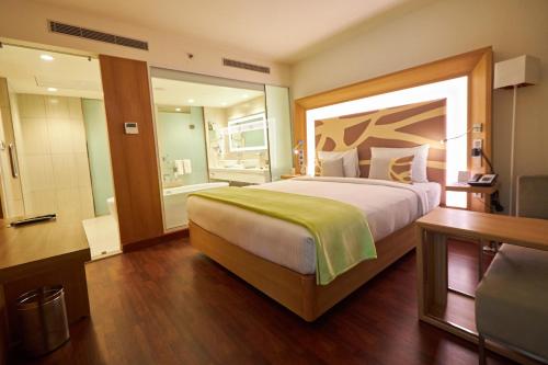 a hotel room with a large bed and a bathroom at Novotel Chennai OMR in Chennai
