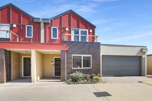 a red house with a garage in a driveway at Apartments on Church 7 - Family Lakeside Escape in Lakes Entrance