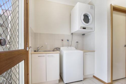 a small kitchen with a refrigerator and a microwave at Apartments on Church - Unit 7 in Lakes Entrance