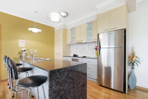 a kitchen with a stainless steel refrigerator and cabinets at Apartments on Church 7 - Family Lakeside Escape in Lakes Entrance