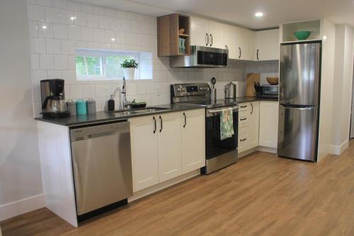 a kitchen with white cabinets and a stainless steel refrigerator at HiddenGem-private modern suite on trendy Main St in Vancouver