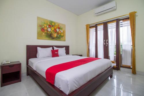 1 dormitorio con 1 cama grande con manta roja en RedDoorz at Benesari 2 Legian, en Kuta