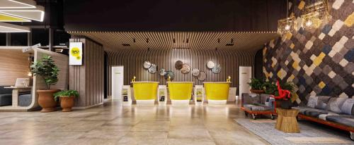 a lobby with yellow chairs and couches in a building at YELLO Hotel Harmoni in Jakarta