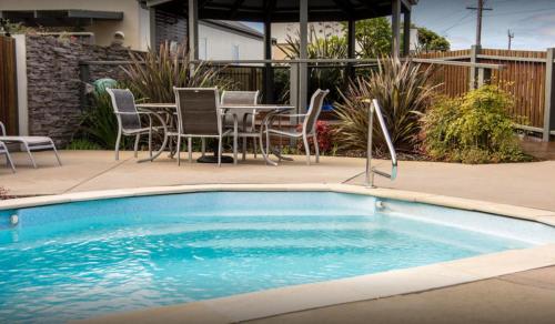 a swimming pool with chairs and a table in a backyard at Apartments on Church 7 - Family Lakeside Escape in Lakes Entrance