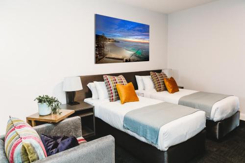 a hotel room with two beds and a couch at Coniston Hotel Wollongong in Wollongong