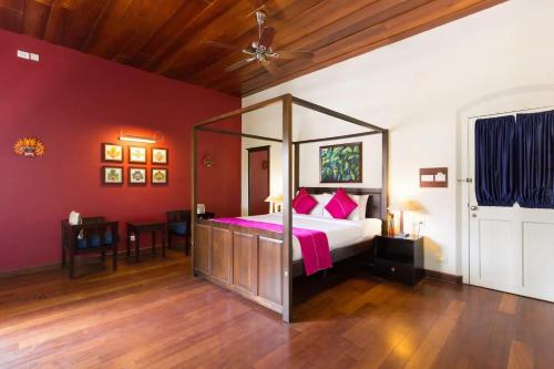a bedroom with a canopy bed with pink pillows at Tea Bungalow in Cochin