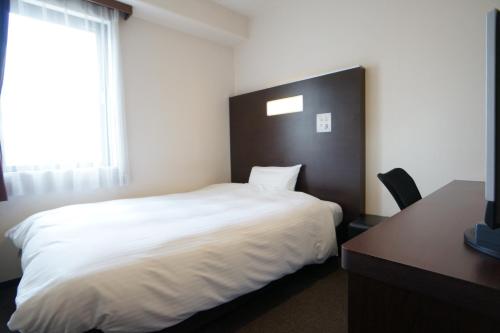 a bedroom with a white bed and a desk and a window at Green Rich Hotel Hiroshima Shinkansenguchi (Artificial hot spring Futamata Yunohana) in Hiroshima