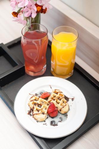 a plate of waffles and strawberries on a tray with drinks at Nava Hotel Tawangmangu in Tawangmangu