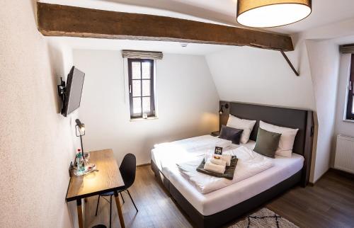 a small bedroom with a bed and a table at STEINHAUS 1718 in Büdingen
