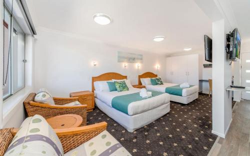 a hotel room with two beds and a couch at Adrift Apartments in Yamba