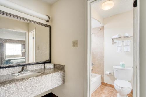 ein Badezimmer mit einem Waschbecken, einem WC und einem Spiegel in der Unterkunft OYO Hotel Alexandria LA- Hwy 165 in Alexandria
