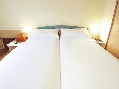 two beds in a hotel room with two lamps at Hotel ibis Setubal in Setúbal
