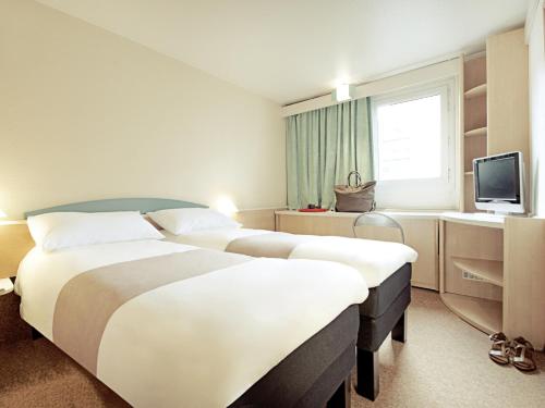 a hotel room with two beds and a television at Hotel ibis Setubal in Setúbal