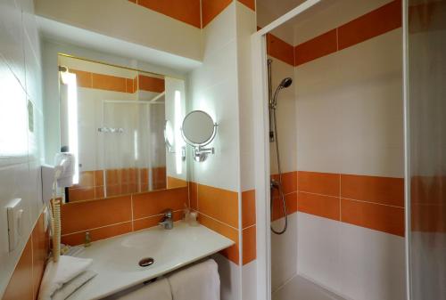 a bathroom with a shower and a sink and a mirror at Comfort Hotel Saintes in Saintes
