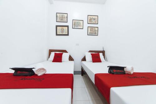 two beds in a room with white walls and red sheets at RedDoorz @ Plaza Jaro Iloilo in Iloilo City