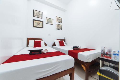 two beds in a room with white walls and red sheets at RedDoorz @ Plaza Jaro Iloilo in Iloilo City
