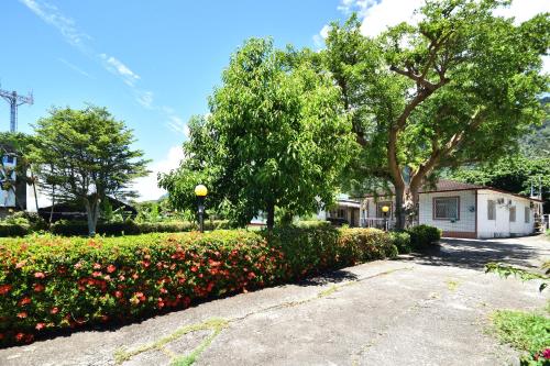 a garden with flowers and trees and a street at Xi Cun Homestay in Donghe