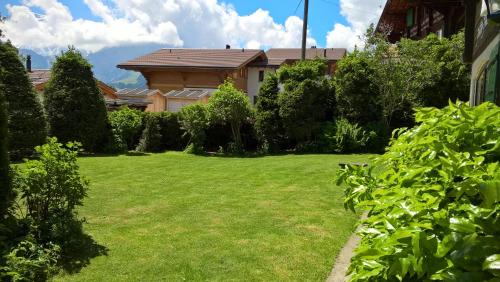 a yard with green grass and a house at Chalet Petite Fleur in Adelboden