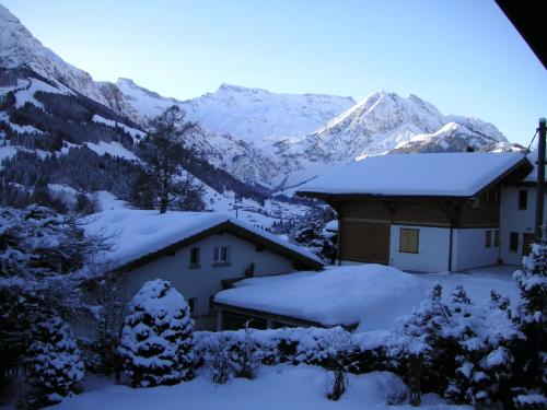 a house covered in snow with mountains in the background at Chalet Petite Fleur in Adelboden