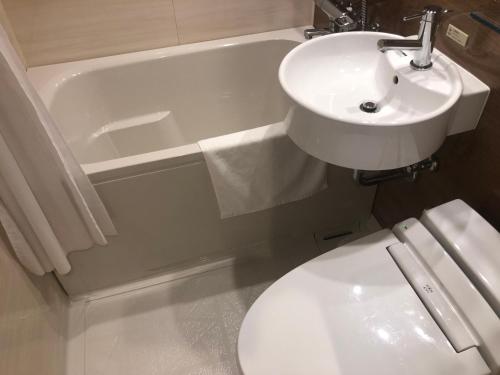 a bathroom with a sink and a toilet and a bath tub at Candeo Hotels Kobe Tor Road in Kobe