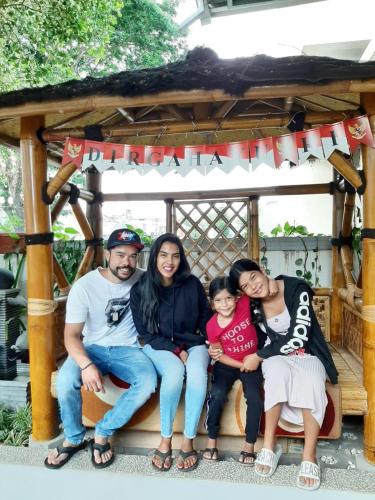 a family sitting on a bench in a gazebo at INNI Homestay in Malang