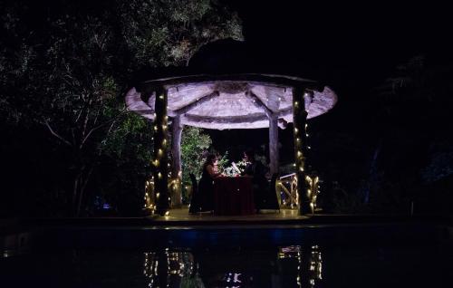 a bride and groom standing under a gazebo at night at Wild Camp- The Nature Resort in Khodāla
