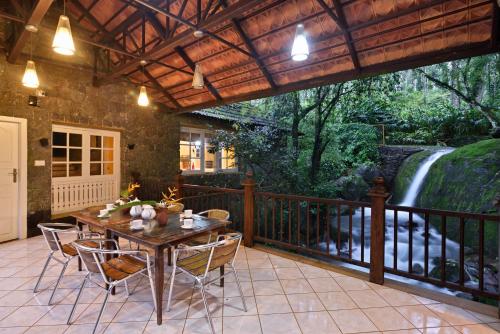 a patio with a table and chairs and a waterfall at Mystic Mayapott, Thekkady in Thekkady