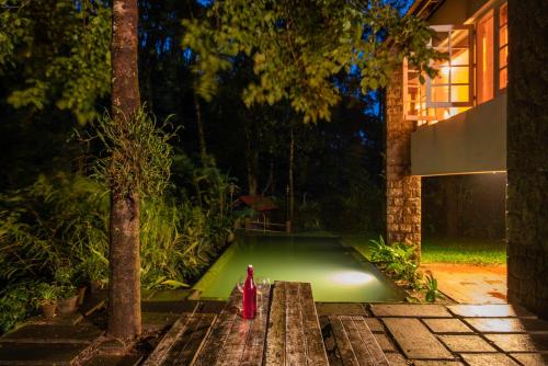 a pool in a garden with a red fire hydrant at Mystic Mayapott, Thekkady in Thekkady