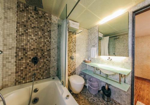 a bathroom with a tub and a sink and a toilet at Hotel Maharana Inn Chembur in Mumbai