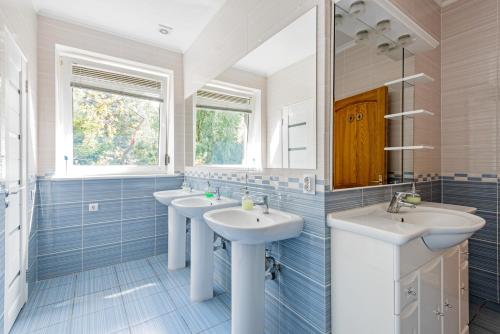 a bathroom with three sinks and two mirrors at Skvorechnik in Kaliningrad