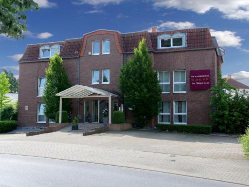 a red brick building with trees in front of it at Designhotel Im Südfeld in Kamen