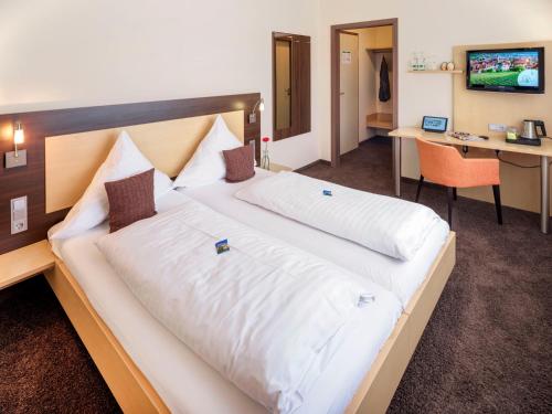 a large bed in a hotel room with a desk at Hotel Berkheimer Hof in Esslingen