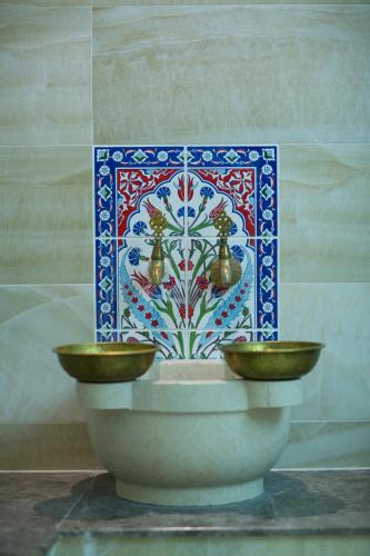 a bowl with two bells in front of a wall at Ruba Palace Thermal Hotel in Bursa