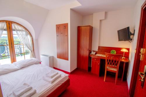 a bedroom with a bed and a desk and a window at Hotel Stary Młyn in Koziegłowy