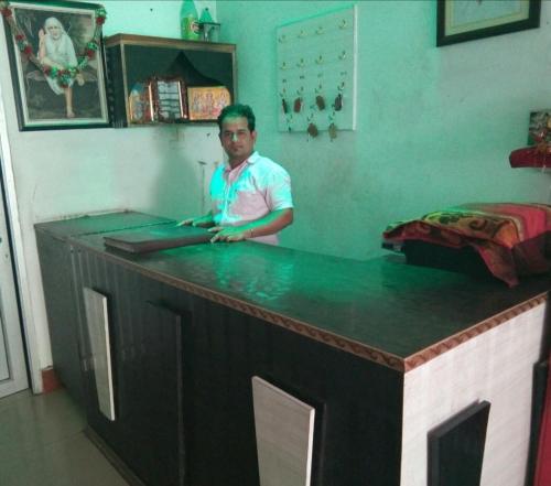 ein Mann steht an einer Bar mit einer grünen Theke in der Unterkunft Sai Guest House in Pathankot