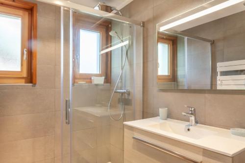 ein Badezimmer mit Dusche, Waschbecken und Spiegel in der Unterkunft BERGERS 1 in Morzine