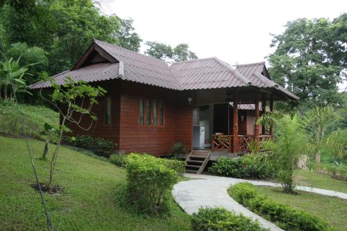 una casa de madera con un camino que conduce a ella en The Thai Elephant Conservation Center Lampang, en Lampang